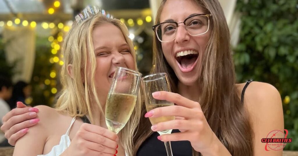 Coco Lovelock and a friend celebrating with champagne, symbolizing her industry achievements and recognition.
